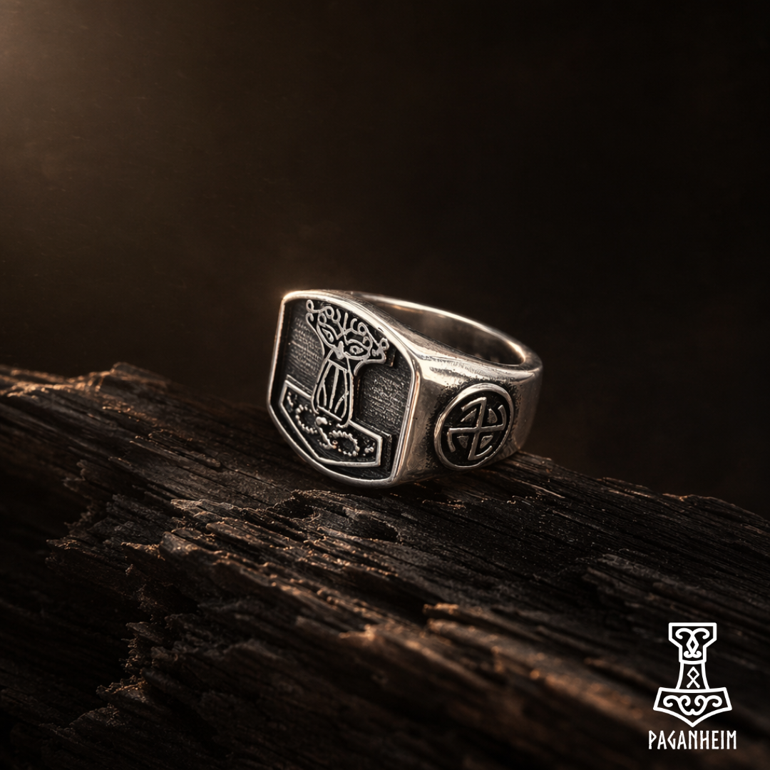 Silver ring with intricate design of the face of Wotan merged into a Mjolnir symbol, and a Sunwheel on its side, on a dark wooden surface, Paganheim logo visible.