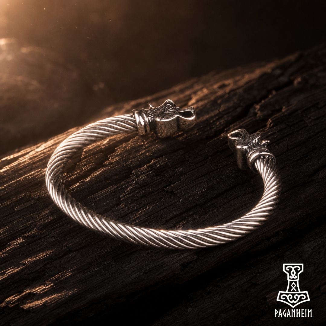 A silver-toned twisted cable bracelet with Viking-style horn clamps, resting on a dark textured wooden surface with dramatic warm lighting.