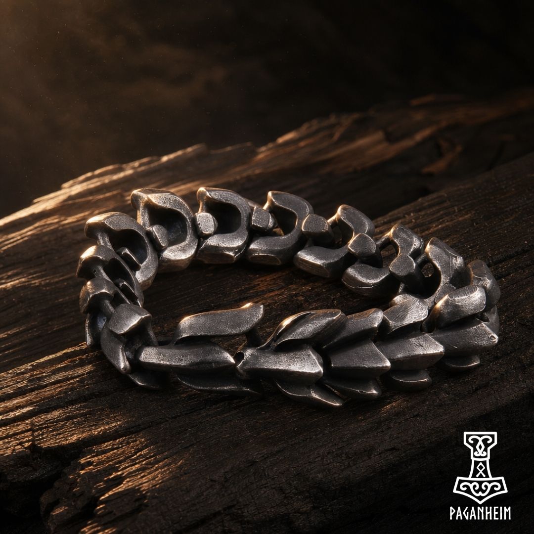 Grey-black Midgard Serpent bracelet resting on dark wood surface under warm light