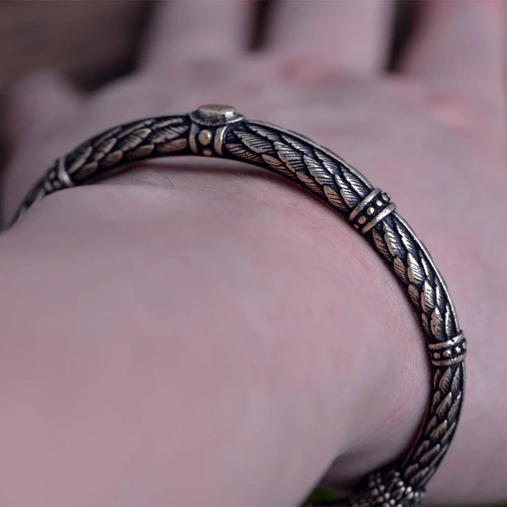 Norse arm ring showcasing raven feather motifs and head details.