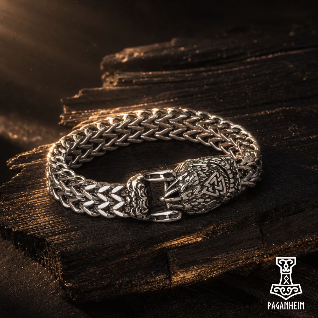A silver-toned Norse-style braided bracelet with a detailed Thor's Hammer clasp, displayed on a dark rustic wooden surface with dramatic warm lighting.