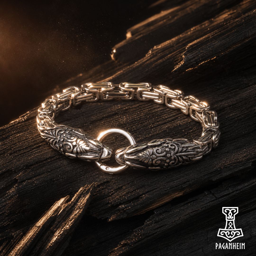 A silver-toned Norse Viking-style chain bracelet with detailed engraved fish motifs and a central ring clasp, displayed on a dark textured wooden surface.