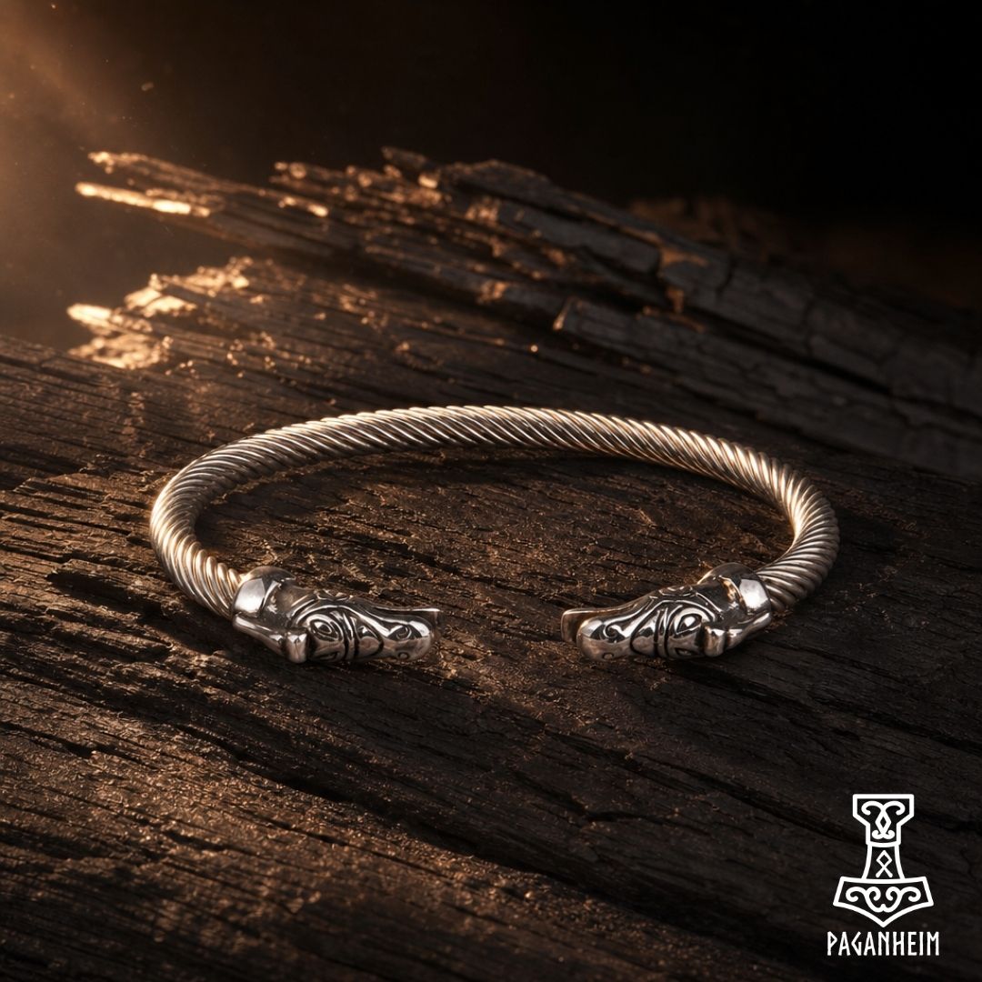 A silver-toned twisted cable cuff bracelet with carved animal-head closures, displayed on dark weathered wood.