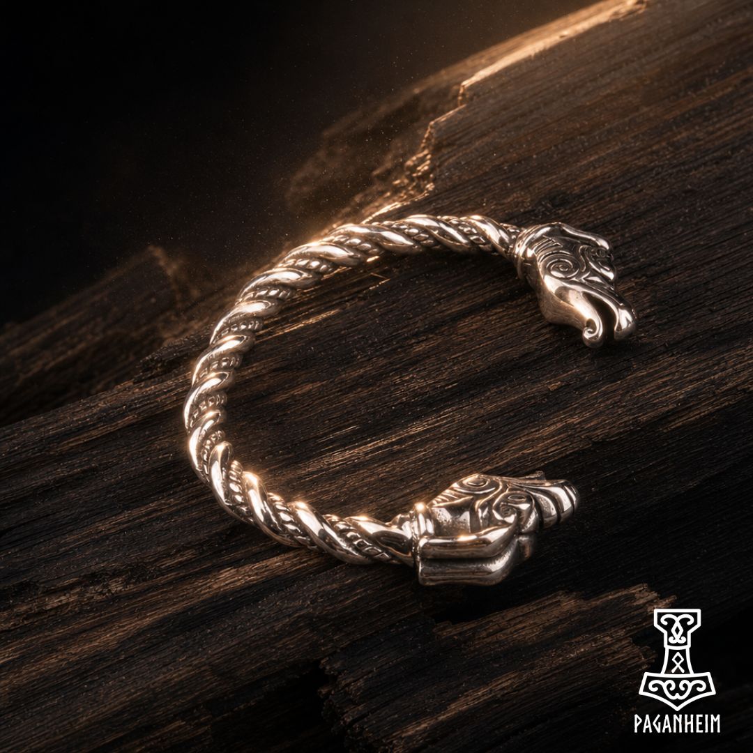 Norse dragon arm ring resting on wooden surface under warm light.