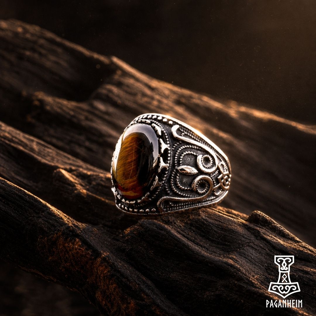 Norse dragon‑inspired ring resting on dark wood surface under warm light