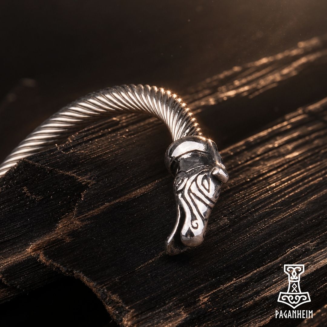 Norse dragon arm ring resting on wooden surface under warm light