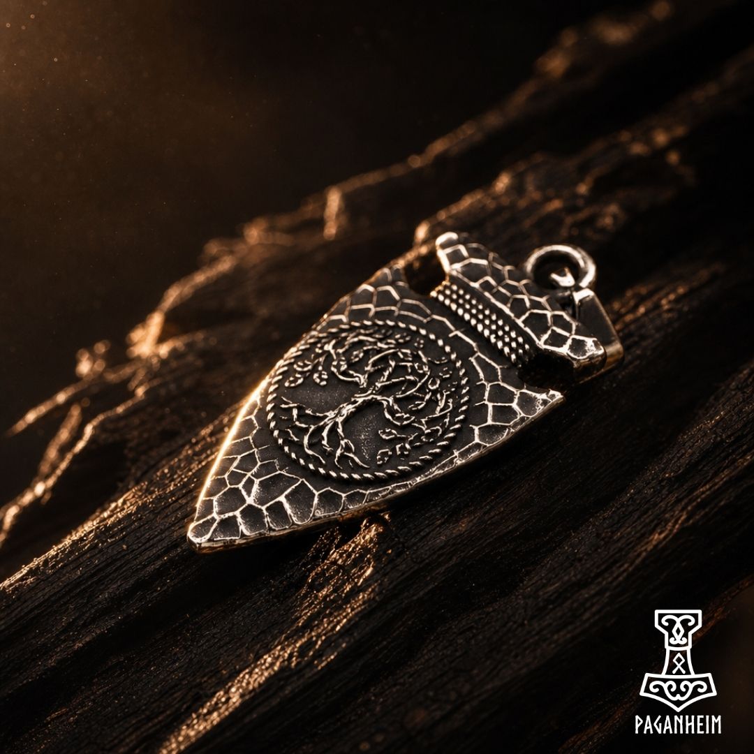 Spearhead pendant resting on rock surface with chain attached.