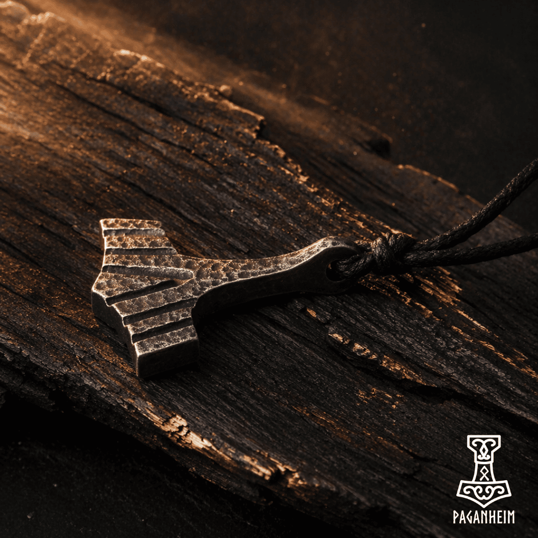 Metal Thor's hammer pendant on a wooden surface with 'Paganheim' branding.