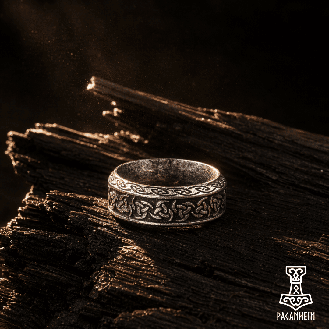 Triskele ring showing triple‑spiral motif in metal engraving.