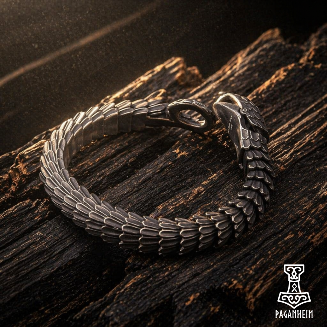 Silver bracelet with dragon design on a wooden surface, featuring the Paganheim brand.
