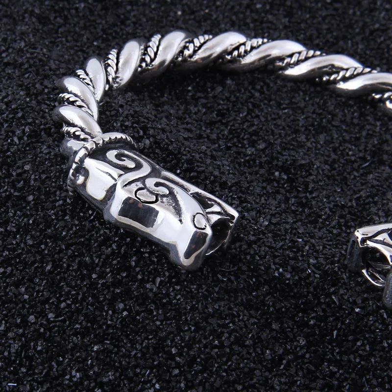 Silver arm ring inspired by Viking hoards with dragon head motifs.