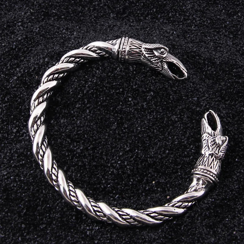 Historical Viking arm ring with a twisted rod design and raven motifs, crafted in silver.