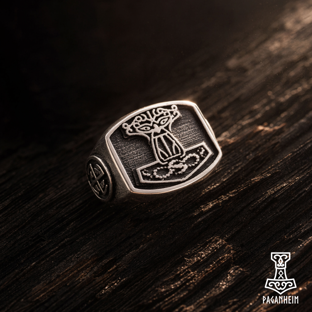 Silver ring with intricate Mjolnir, Odin and Sunwheel symbology, on a wooden surface, featuring the brand 'Paganheim'.