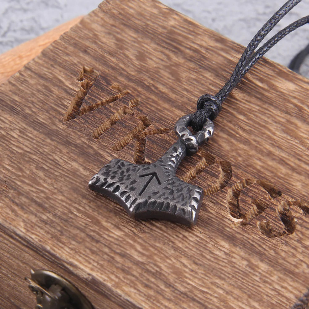 Close-up of an ancient-looking Mjölnir pendant adorned with the Tiwaz rune.