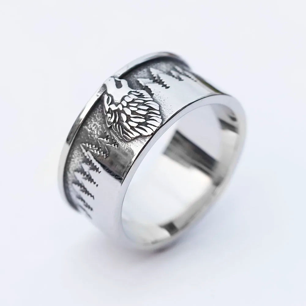 Nature-inspired ring with wolf and pine tree engravings.