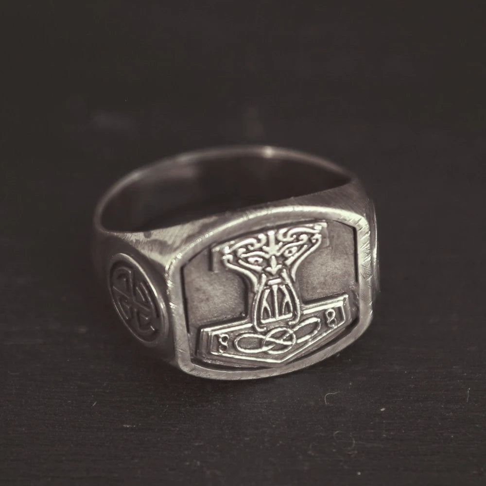 A silver stainless steel signet ring with a Norse/Viking amulet design on a dark background.