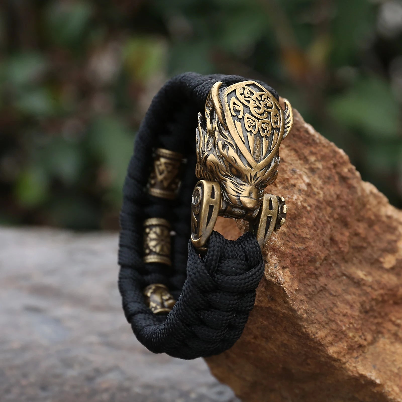 Bear head clasp on paracord bracelet with Norse symbols.