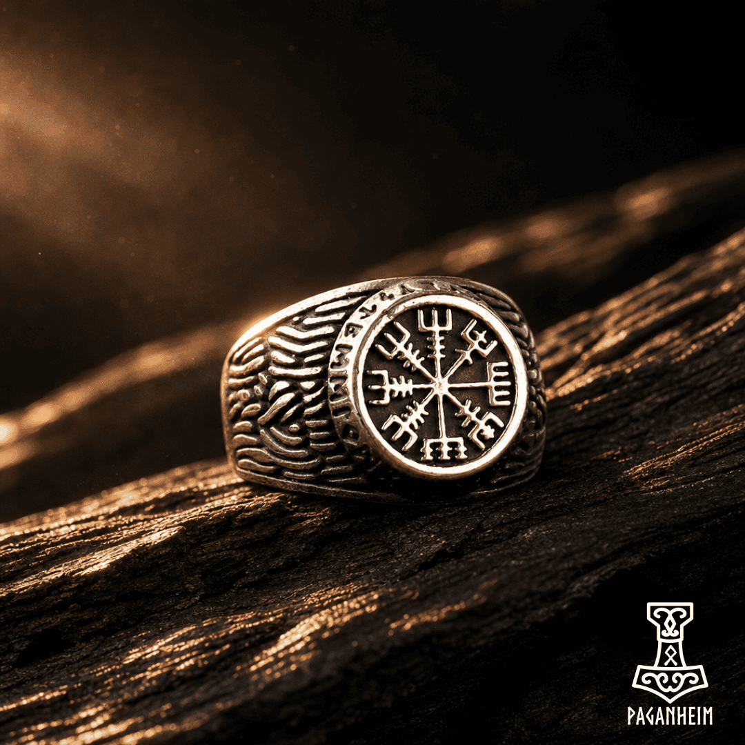 A silver-toned Viking-style ring with a Vegvisir compass emblem and carved knotwork details, resting on a dark textured wooden surface with dramatic warm lighting.