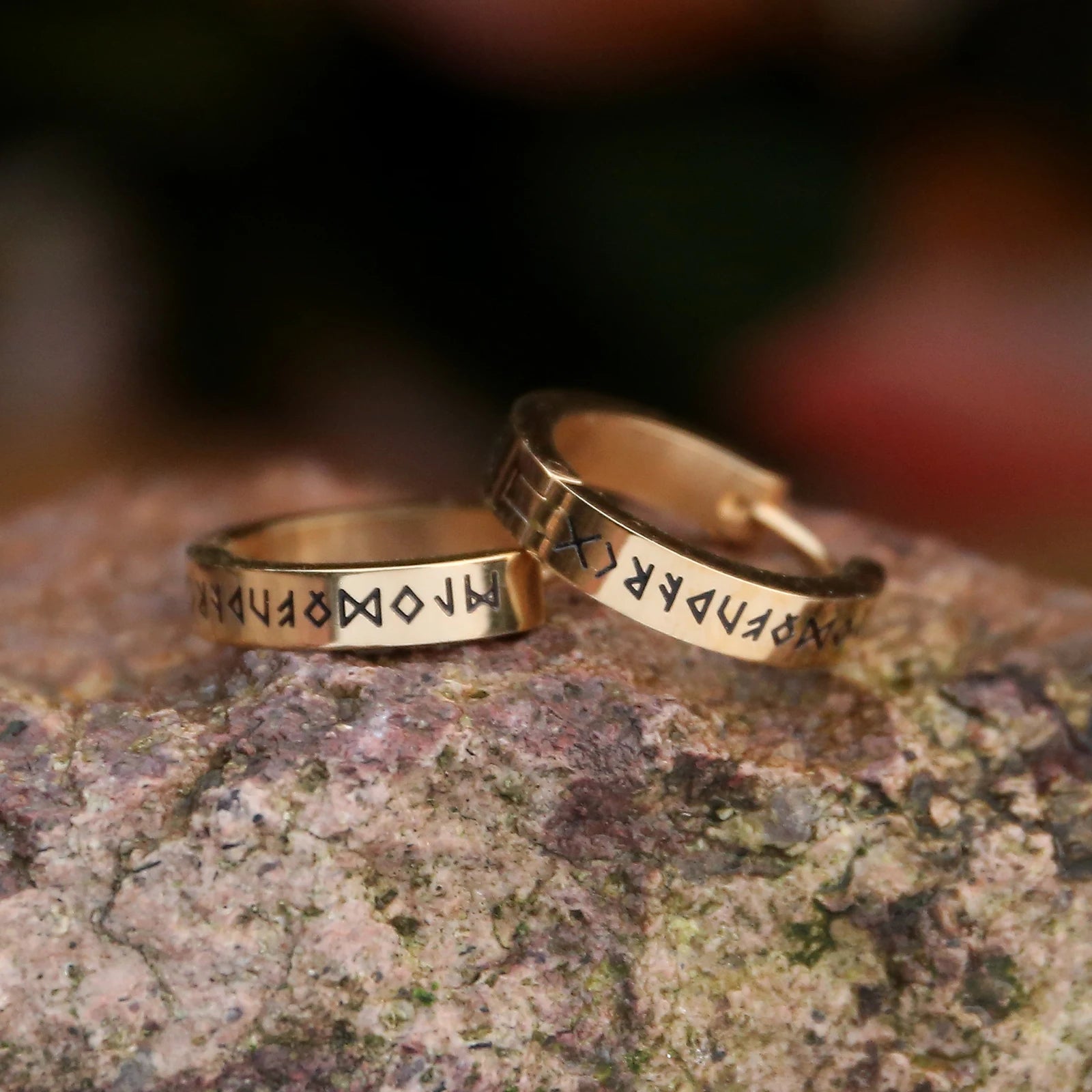 Gold Viking-style earrings etched with Elder Futhark runes.