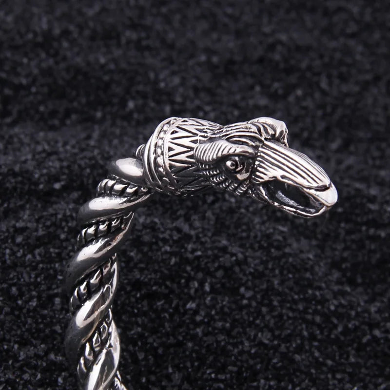 Twisted rod arm ring crafted in sterling silver with raven head motifs, inspired by Norse artifacts.