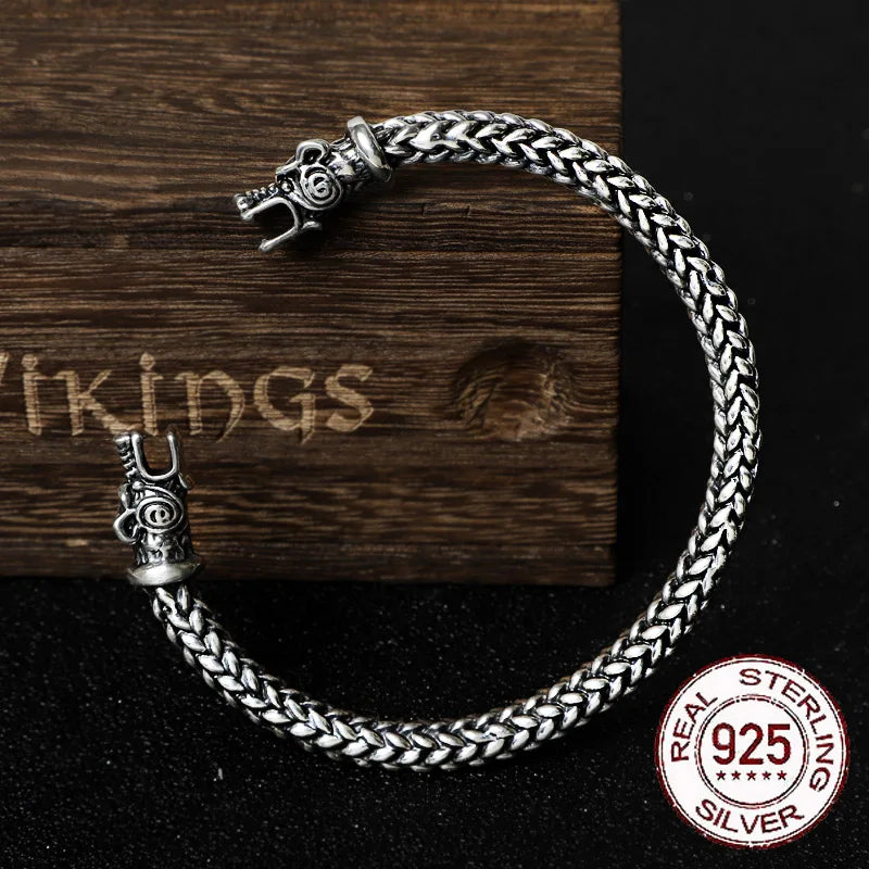 Sterling silver rod arm ring with plaited design and bear head ends, inspired by Viking artifacts.